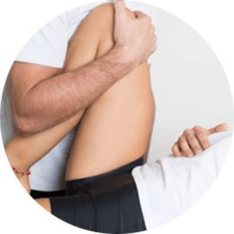Ostéopathe manipulant le genou d'un homme allongé sur le dos.