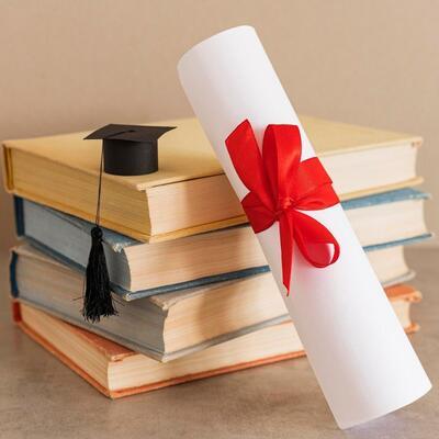 Un chapeau et un diplôme de fin d'études reposant sur une pile de livres, symbolisant la réussite scolaire et le succès.