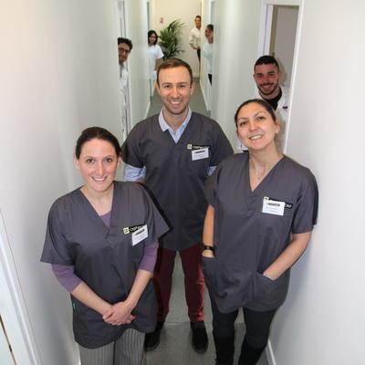 Trois professeurs et leurs élèves derrière eux dans un couloir de l'école d'ostéopathie Ostéobio Paris