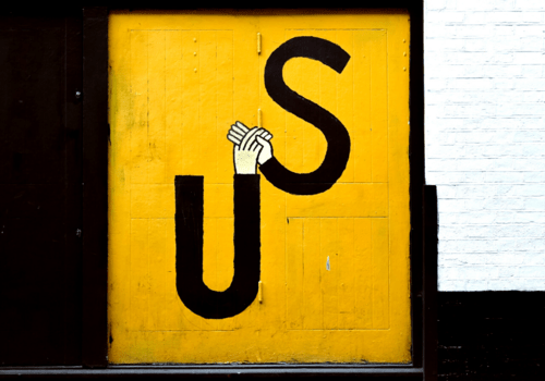 Graffiti représentant deux mains qui se rejoignent et forme un "US", nous en anglais.