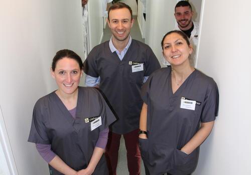 Trois professeurs et leurs élèves derrière eux dans un couloir de l'école d'ostéopathie Ostéobio Paris