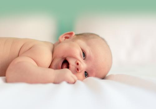 bébé posant sur le ventre en souriant