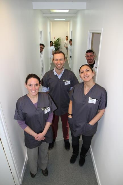 Trois professeurs et leurs élèves derrière eux dans un couloir de l'école d'ostéopathie Ostéobio Paris